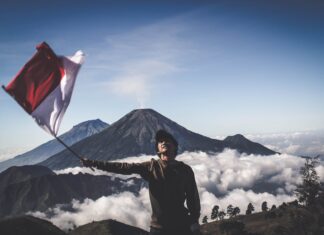 Mann mit indonesischer Flagge vor Vulkan