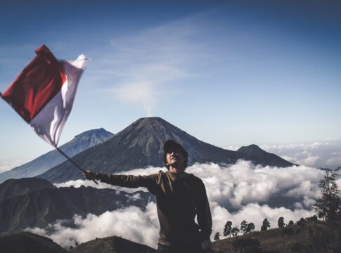 Mann mit indonesischer Flagge vor Vulkan