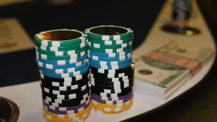 150000-euro-garantie-sixers-main-event-barcelona Zwei Stapel mit Pokerchips und ein Bündel Geldscheine auf einem Pokertisch