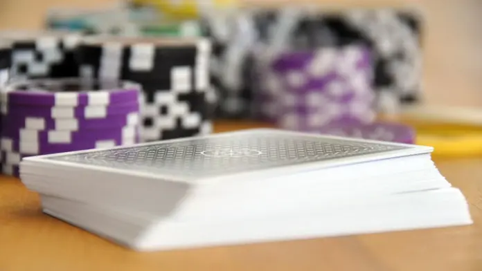 angebliche-fuenf-prozent-ggpoker-kenney-fordert-millionen Ein Stapel Spielkarten und Pokerchips auf einem Holztisch