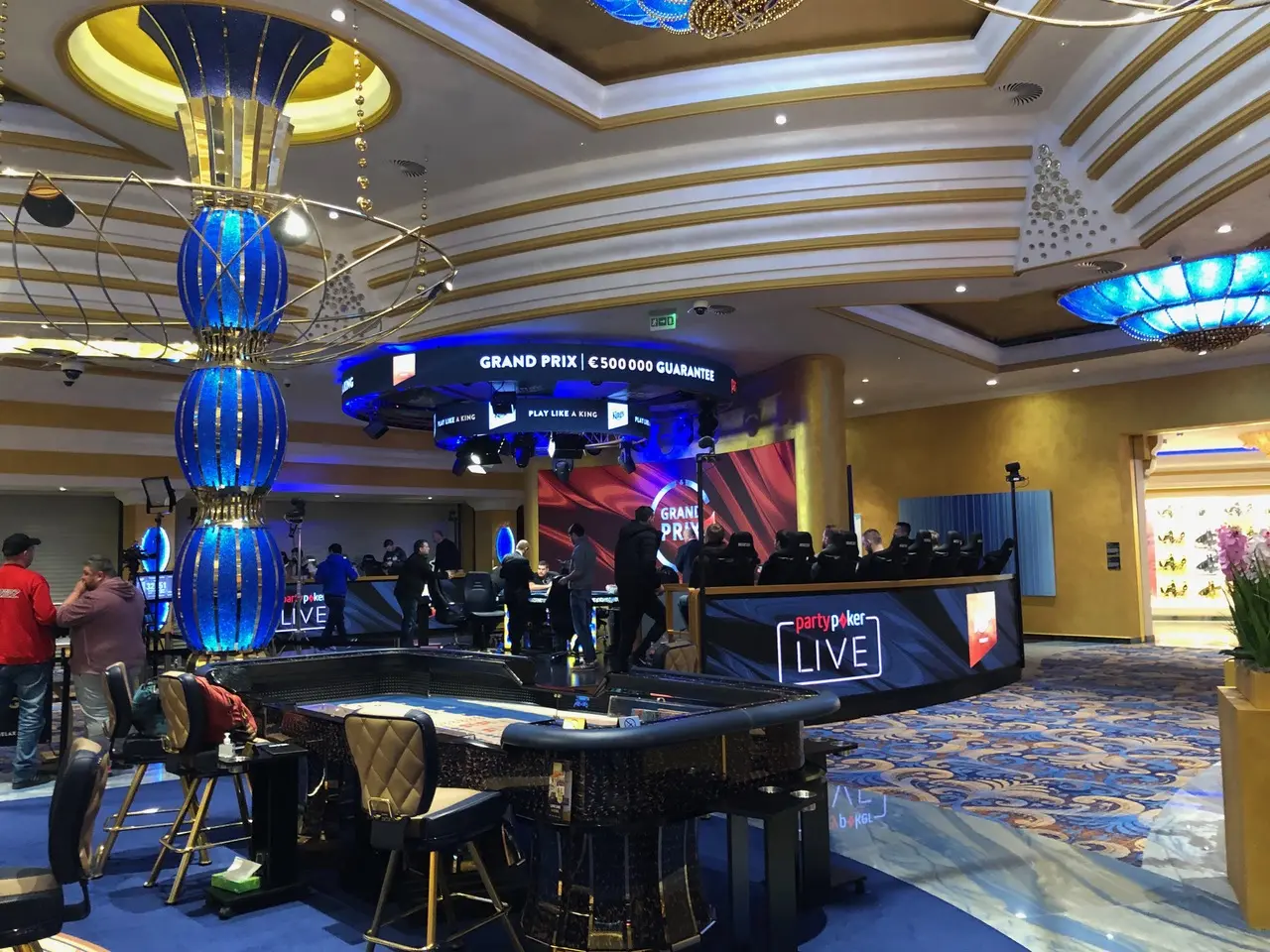 Innenansicht eines Casinos mit Pokertischen und einer Anzeige für den Grand Prix.