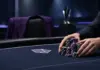 Nicholas Palma feiert ersten Titel auf der PokerGO Tour Anonyme Hände sammeln Pokerchips am Turniertisch neben einem violetten Sakko