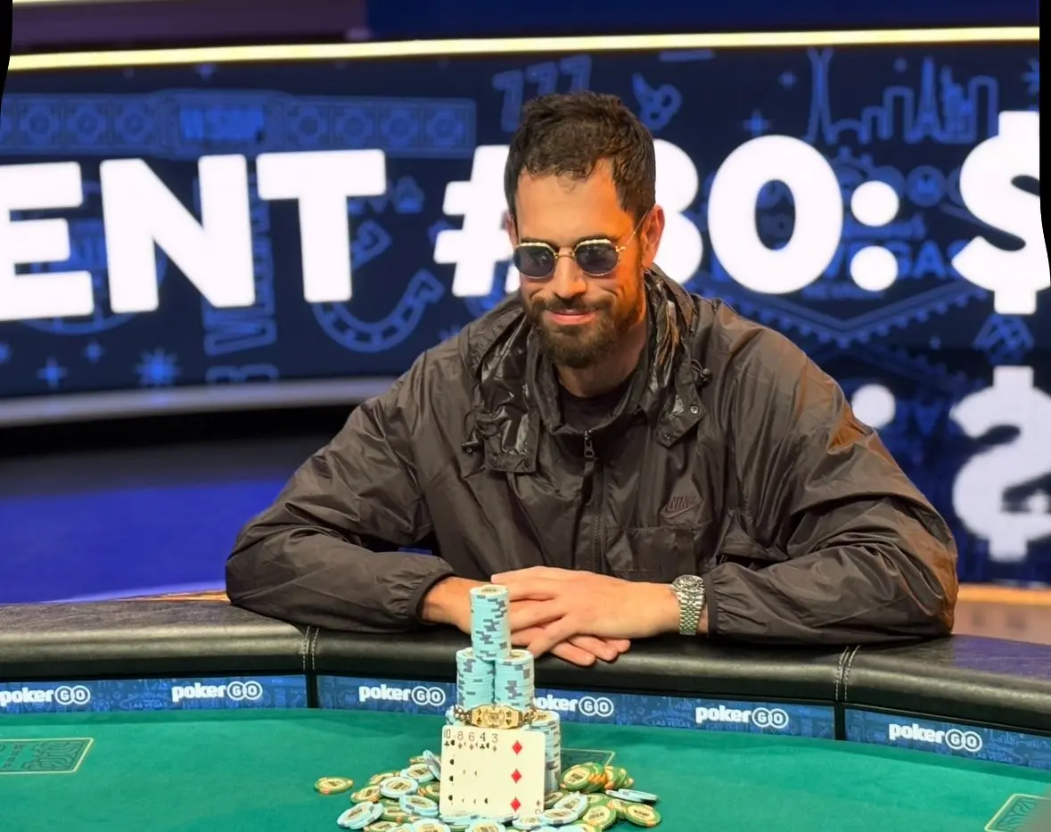 Nick Schulman mit Sonnenbrille an einem Pokertisch vor Poker chips.