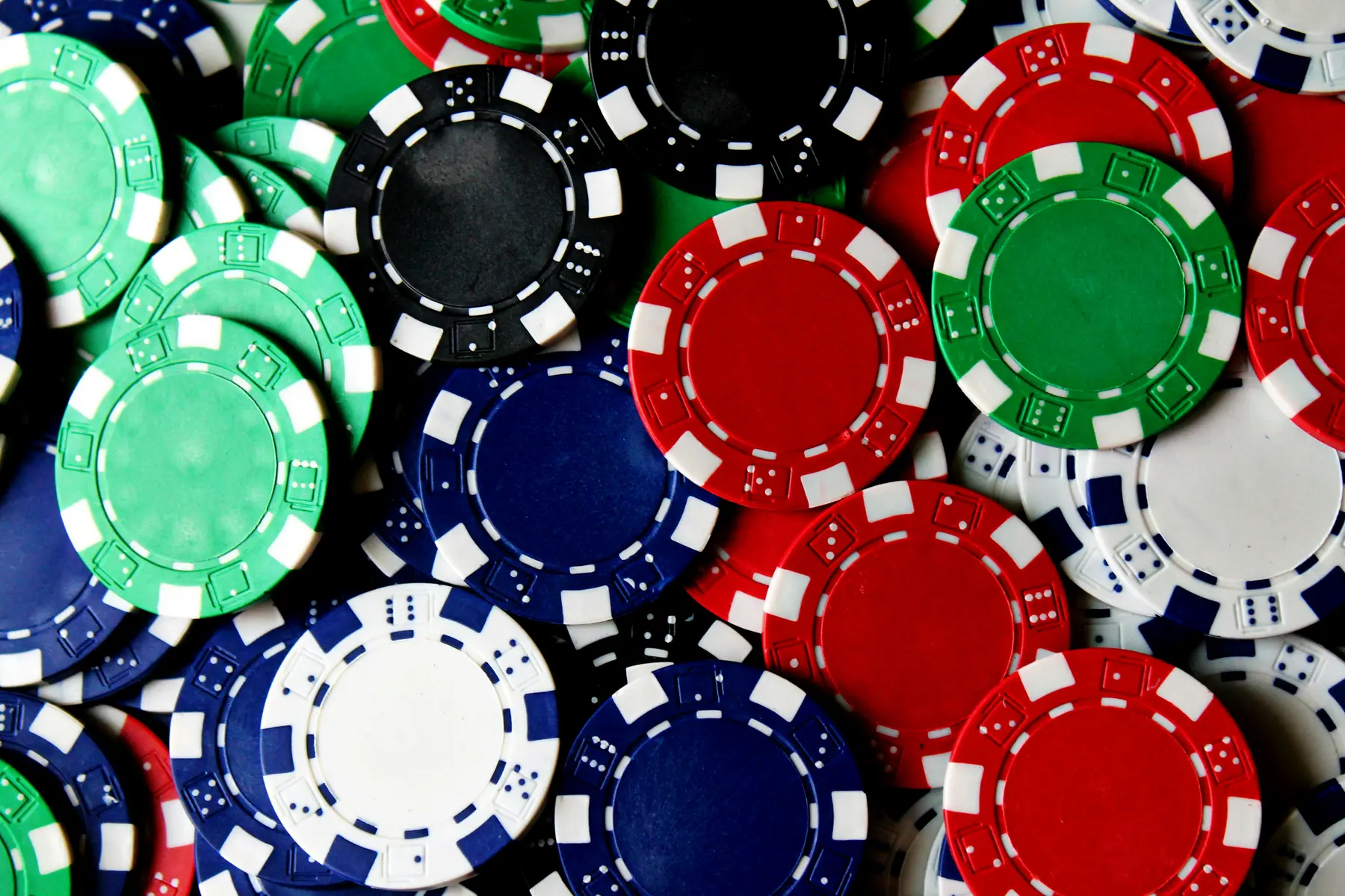 Eine Nahaufnahme von verschiedenen bunten Pokerchips in Rot, Blau, Grün und Schwarz.