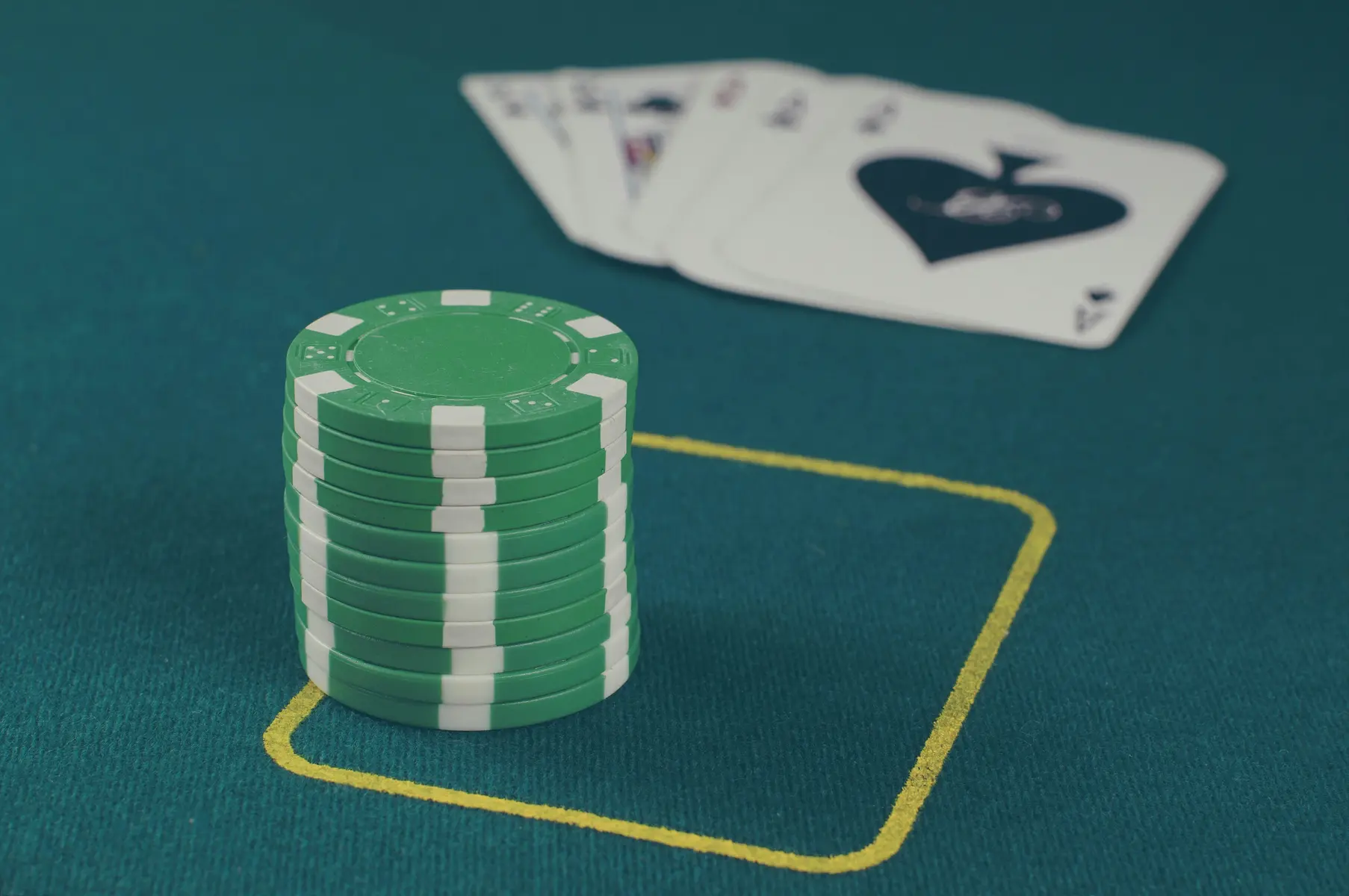 Ein Stapel grüner Pokerchips und Spielkarten auf einem grünen Pokertisch