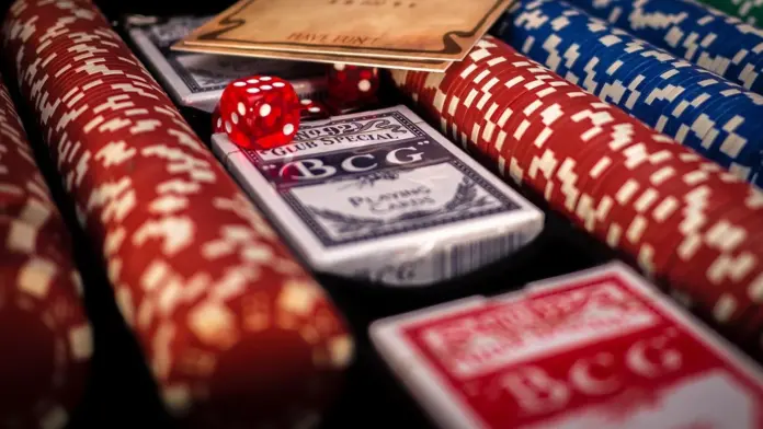 river-flush-cesar-garcia-erster-pgt-titel Pokerchips, Spielkarten und rote Würfel auf einem Tisch.