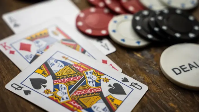 slide-dealing-im-venetian-schutz-vor-kameras Spielkarten und Casino-Chips auf einem Holztisch, inklusive eines Dealer-Buttons