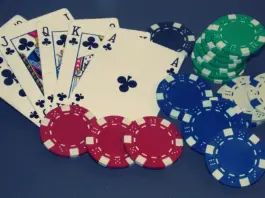 Pokerkarten mit einem Royal Flush in Treff und verschiedene farbige Pokerchips auf dunklem Hintergrund